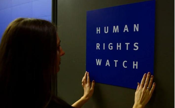 Una mujer coloca un logotipo del grupo de derechos estadounidense Human Rights Watch en la puerta el 21 de enero de 2014 en Berlín [JOHN MACDOUGALL/AFP vía Getty Images].