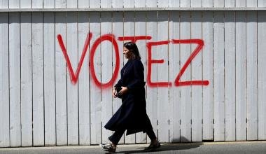 A woman walks past graffiti on a fence that reads, 'Vote', in Paris, France.Photographer: Emmanuel Dunand/AFP/Getty Images