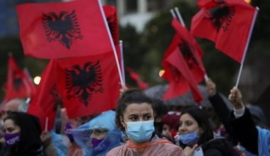 A woman looks on as people wave Albanian flags during a Socialist Party election rally in Tirana, Albania April 22, 2021. REUTERS/Florion Goga