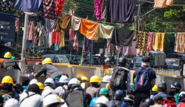 Protesters against the military coup in Myanmar are surrounded by women’s clothes which have been hung in the streets to keep soldiers and police away [Stringer/Anadolu]